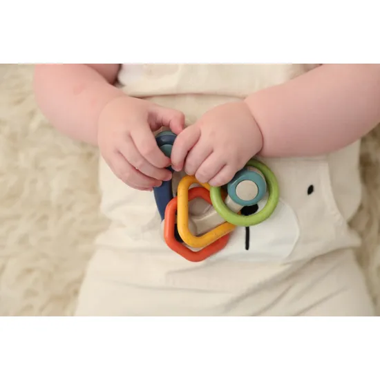 Színes, háromszög alakú csörgő három különböző formájú medállal.